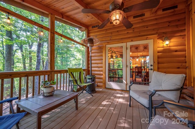 unfurnished sunroom featuring ceiling fan, beamed ceiling, and wooden ceiling