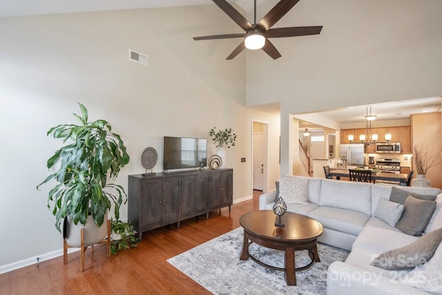 living room featuring wood-type flooring, high vaulted ceiling, and ceiling fan