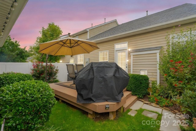 back house at dusk featuring a wooden deck