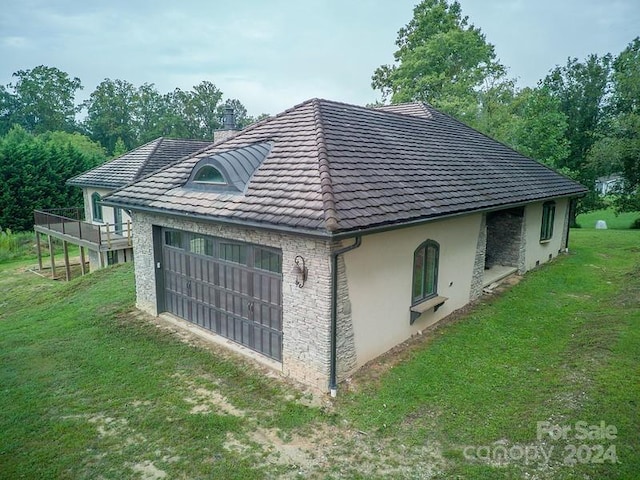 view of side of home with stucco siding, a chimney, a detached garage, and a yard