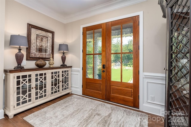 entryway with wood tiled floor, french doors, wainscoting, crown molding, and a decorative wall