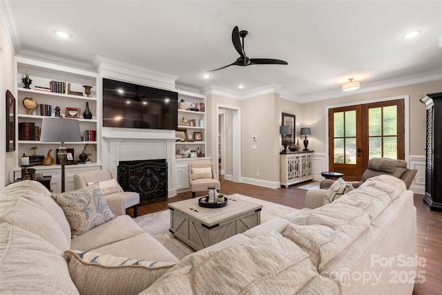 living area with wood finished floors, recessed lighting, french doors, a fireplace, and crown molding