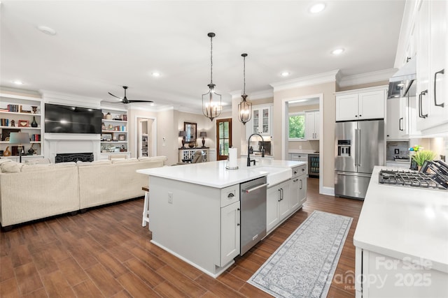 kitchen with a sink, light countertops, stainless steel appliances, white cabinetry, and a kitchen island with sink