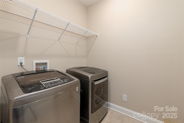 laundry area featuring laundry area, light tile patterned floors, washing machine and dryer, and baseboards