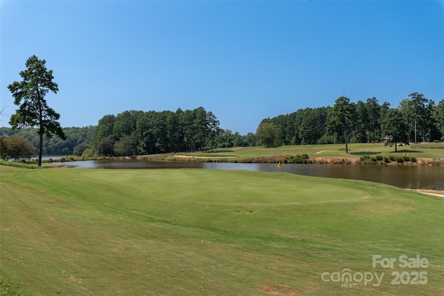 view of property's community with view of golf course, a lawn, and a water view