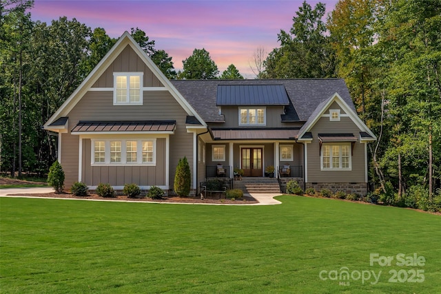 craftsman-style house featuring a standing seam roof, board and batten siding, a lawn, and covered porch