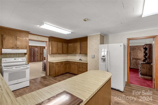 kitchen with crown molding, light colored carpet, and white appliances