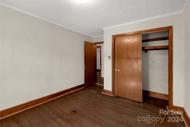 unfurnished bedroom featuring ornamental molding, dark wood-type flooring, and a closet