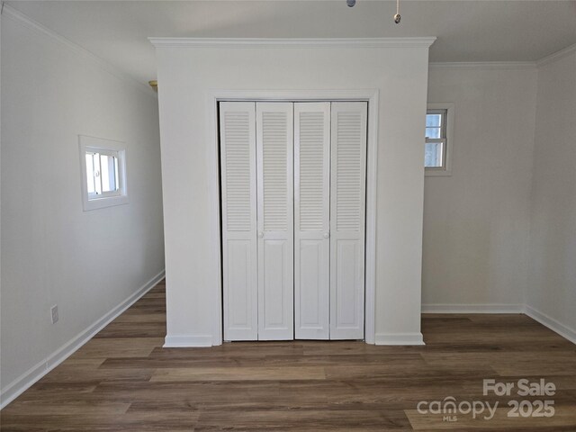 unfurnished bedroom featuring crown molding, dark hardwood / wood-style flooring, and a closet