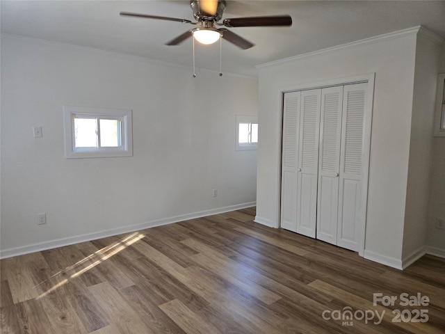 unfurnished bedroom featuring crown molding, dark wood-type flooring, a closet, and ceiling fan