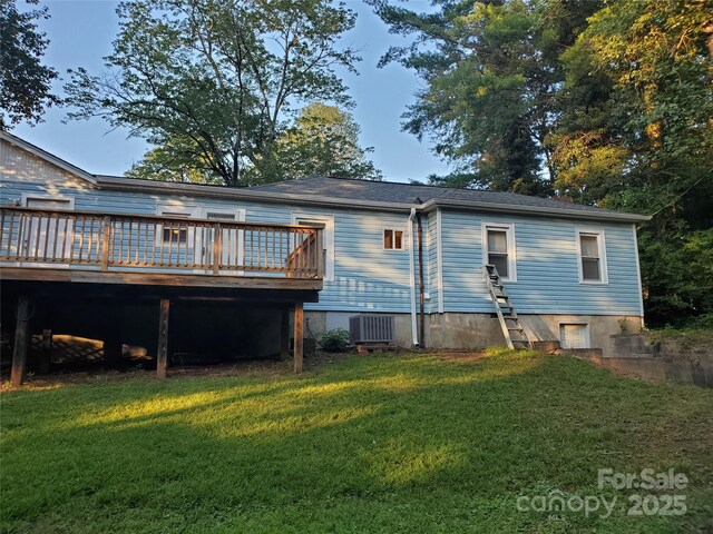 rear view of house featuring cooling unit, a wooden deck, and a lawn