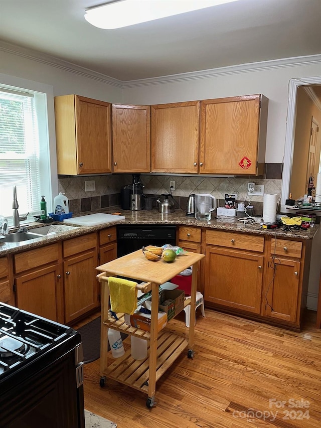 kitchen featuring light wood finished floors, a sink, tasteful backsplash, gas range oven, and dishwasher