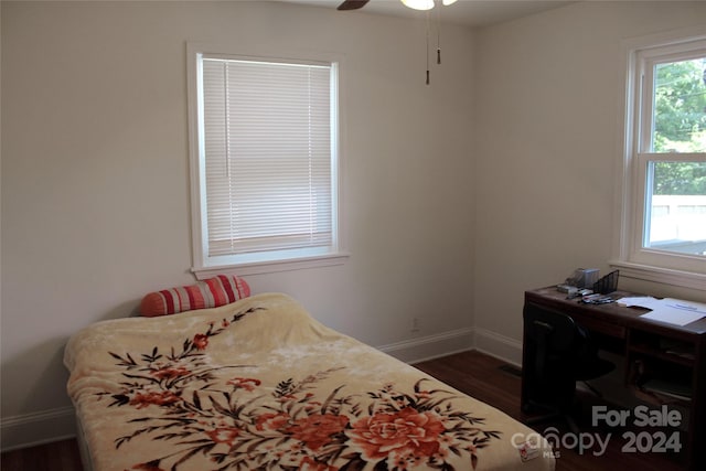 bedroom featuring multiple windows, baseboards, ceiling fan, and dark wood finished floors
