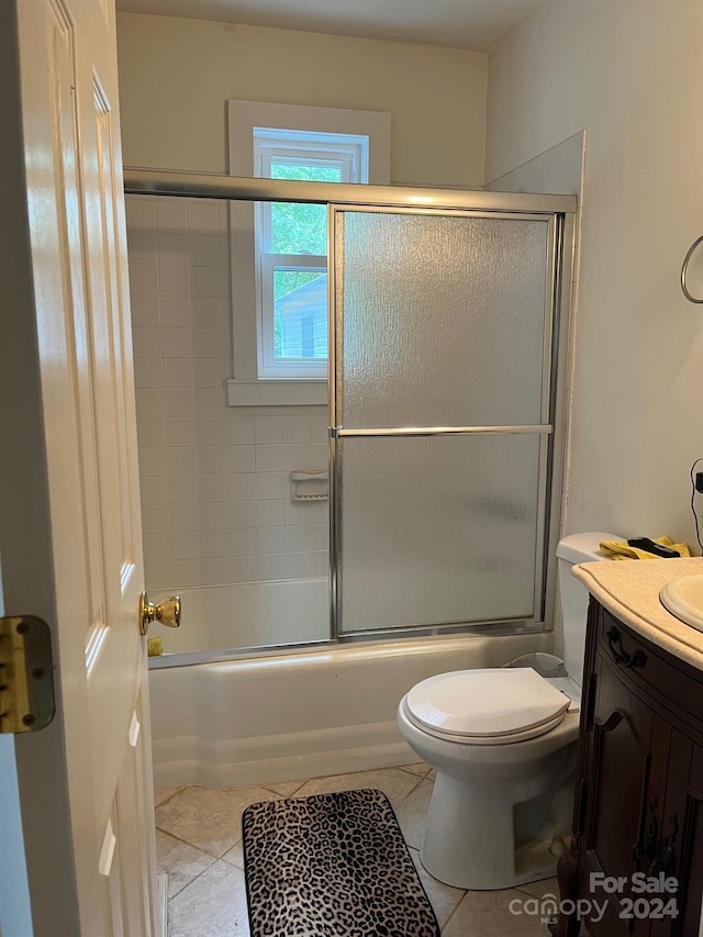 bathroom with tile patterned floors, vanity, toilet, and bath / shower combo with glass door