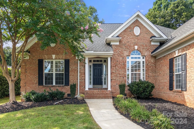 traditional home featuring brick siding, a shingled roof, and a front yard