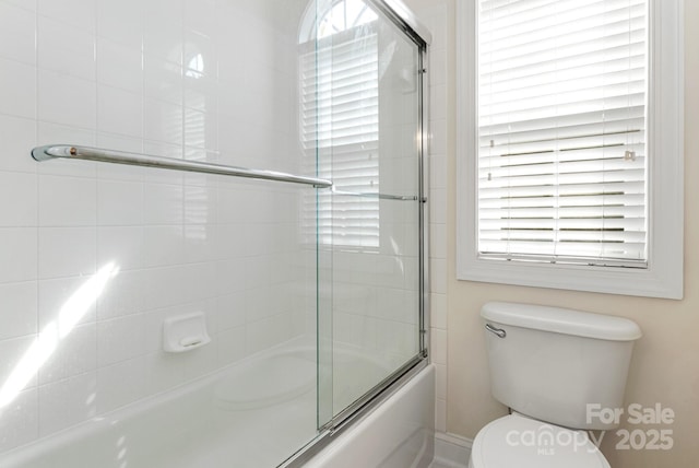 bathroom with combined bath / shower with glass door and toilet
