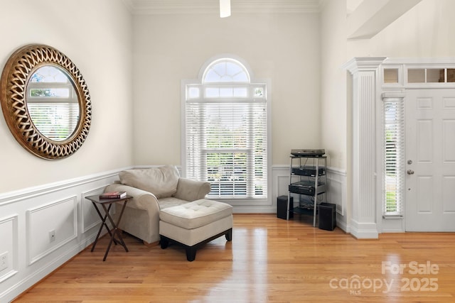 sitting room with wainscoting, light wood-style floors, and ornamental molding