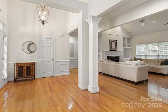 foyer with a fireplace, decorative columns, a ceiling fan, and light wood-style floors