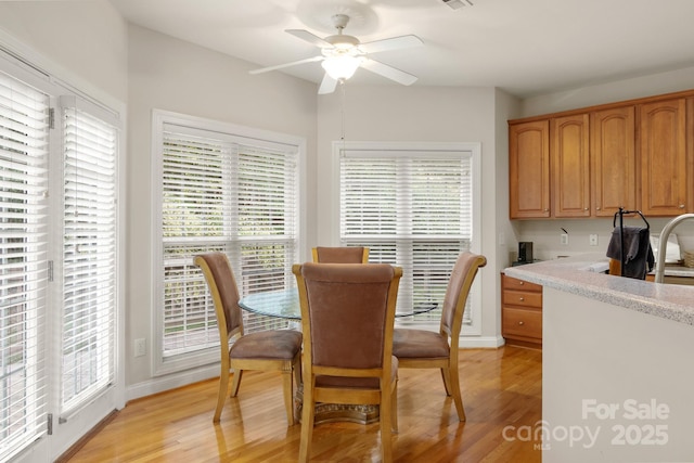 dining area with a ceiling fan, light wood-style floors, and baseboards