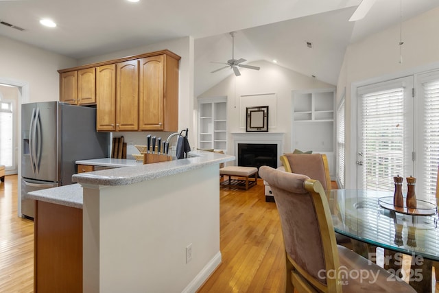 kitchen with a ceiling fan, visible vents, light wood-type flooring, vaulted ceiling, and stainless steel fridge