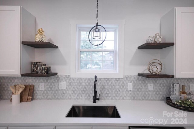 kitchen with white cabinets, decorative backsplash, a chandelier, and sink