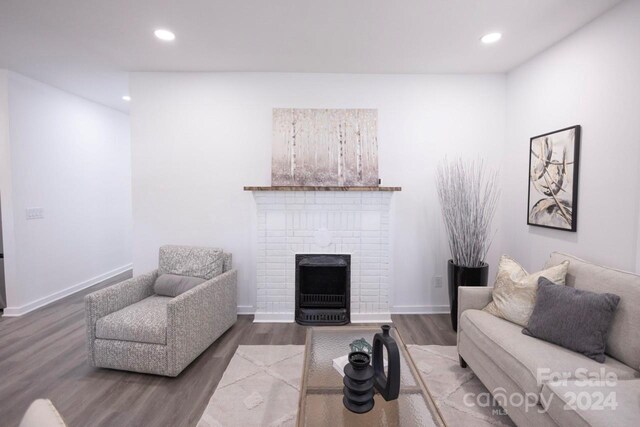 living room featuring a brick fireplace and dark hardwood / wood-style flooring