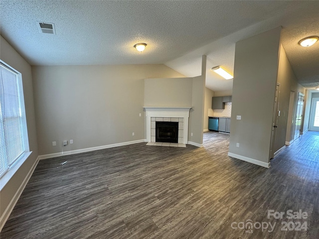 unfurnished living room featuring vaulted ceiling, a fireplace, a textured ceiling, and dark hardwood / wood-style flooring