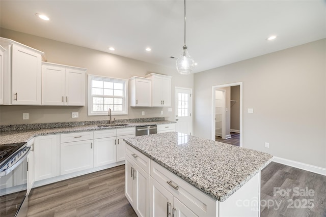 kitchen featuring sink, stainless steel appliances, white cabinets, a kitchen island, and decorative light fixtures