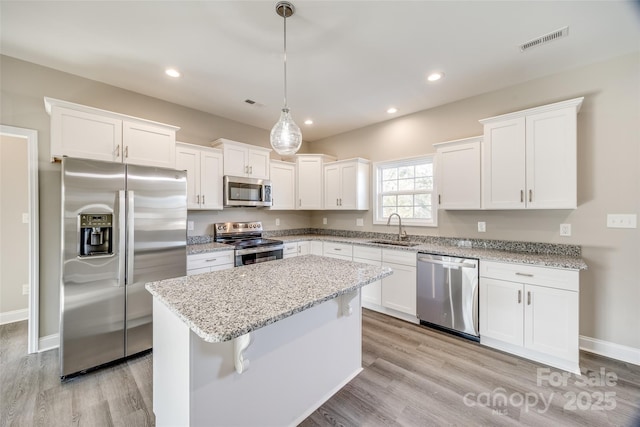 kitchen with sink, a center island, pendant lighting, stainless steel appliances, and white cabinets