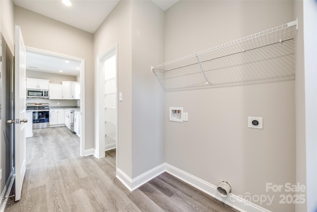 clothes washing area with washer hookup, hookup for an electric dryer, and light wood-type flooring