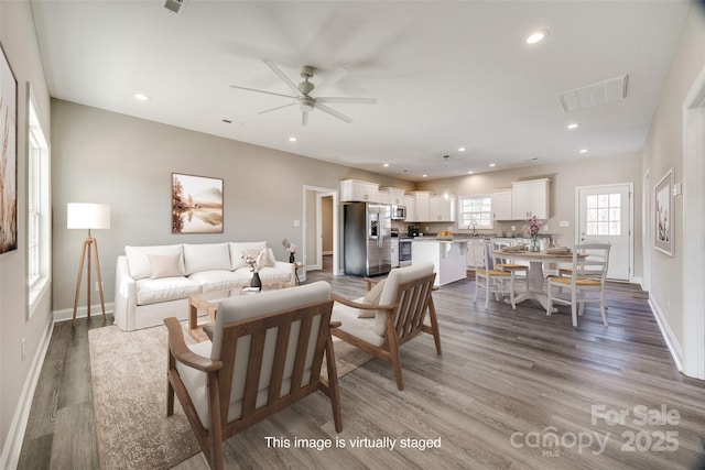 living room featuring ceiling fan, sink, and light hardwood / wood-style floors