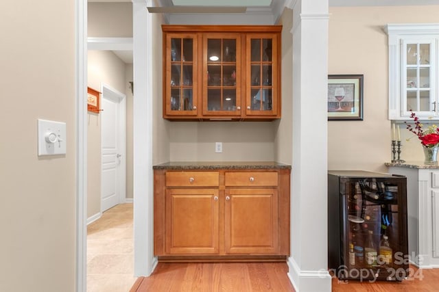 bar with dark stone counters and light hardwood / wood-style flooring