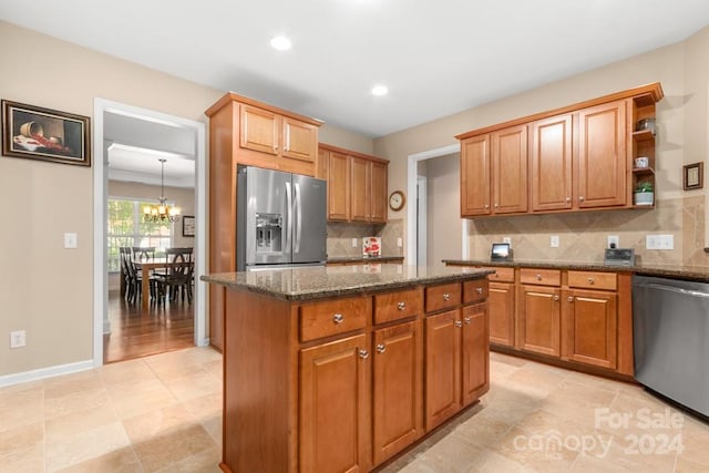 kitchen with a kitchen island, backsplash, stainless steel appliances, a chandelier, and dark stone countertops