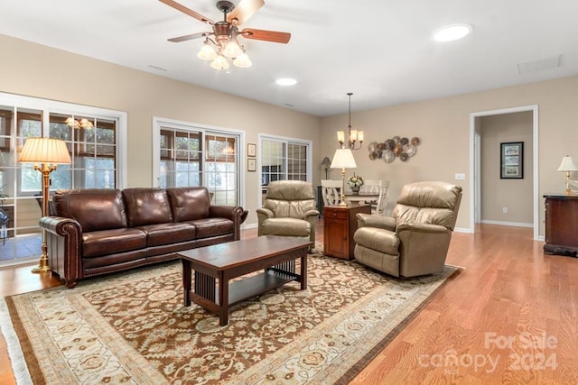 living room with ceiling fan with notable chandelier and light hardwood / wood-style floors