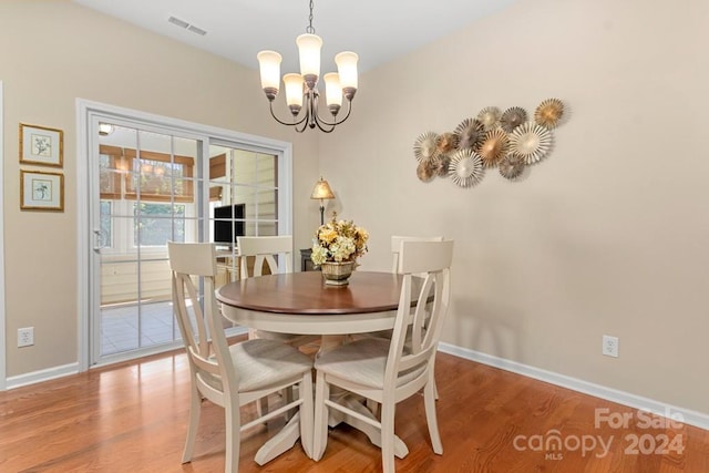 dining space featuring hardwood / wood-style floors and an inviting chandelier