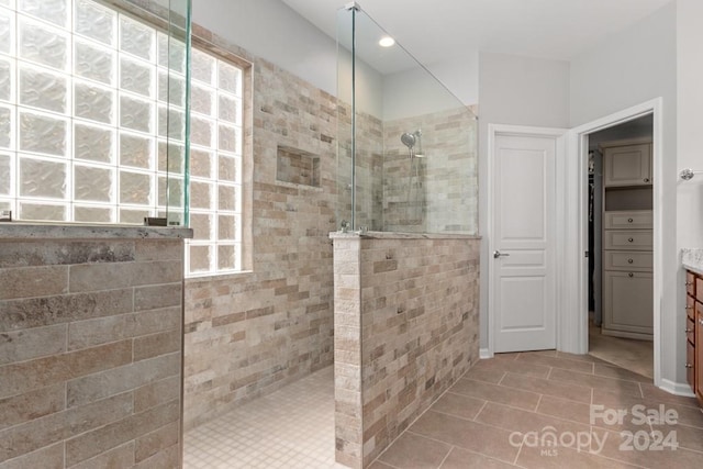 bathroom featuring tile patterned floors, tile walls, a tile shower, and vanity