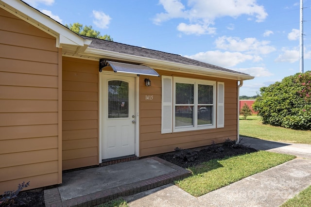 entrance to property featuring roof with shingles