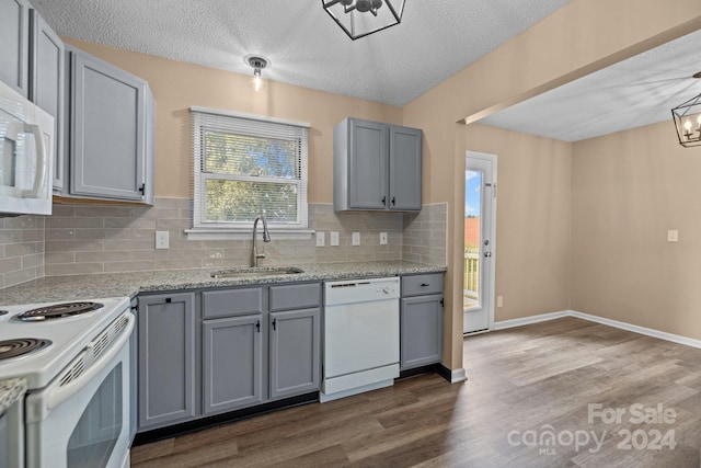 kitchen with a sink, white appliances, gray cabinets, and dark wood finished floors