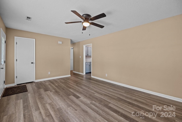 unfurnished room featuring a textured ceiling, wood finished floors, a ceiling fan, and baseboards