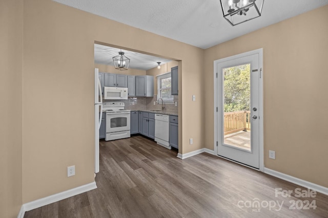 kitchen featuring white appliances, dark wood-type flooring, a sink, baseboards, and decorative backsplash