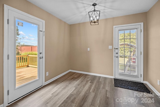 entryway with an inviting chandelier, wood finished floors, and baseboards