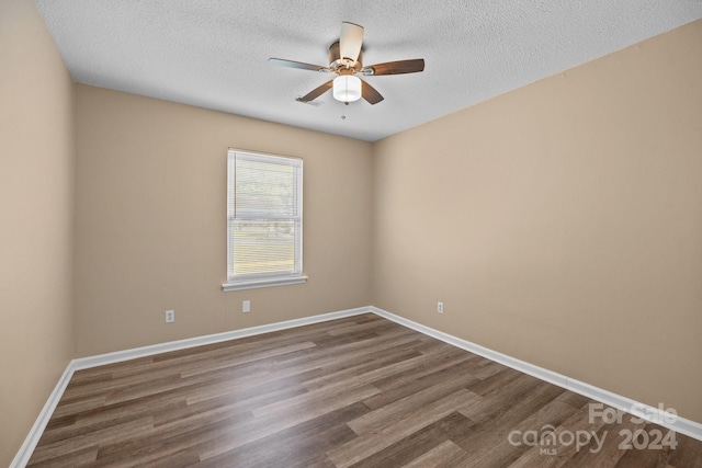 unfurnished room featuring ceiling fan, dark wood-type flooring, a textured ceiling, and baseboards