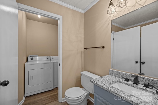 bathroom featuring a textured ceiling, toilet, wood finished floors, washer and dryer, and ornamental molding