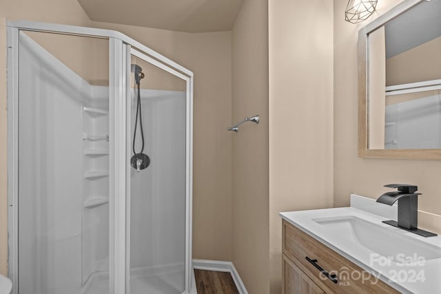 bathroom featuring a stall shower, wood finished floors, vanity, and baseboards