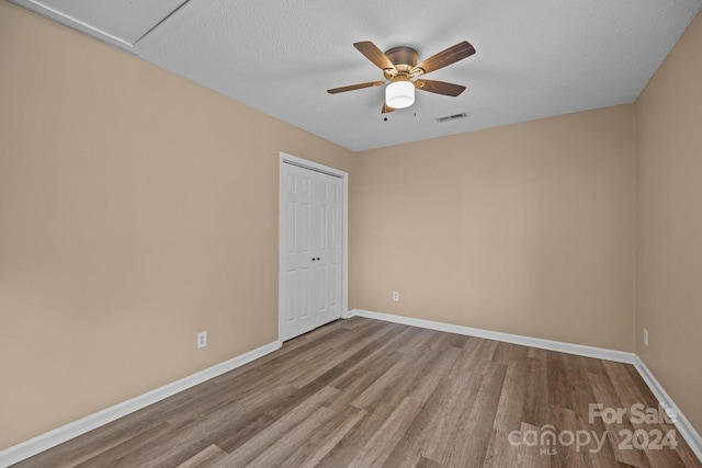 empty room featuring ceiling fan, a textured ceiling, wood finished floors, visible vents, and baseboards