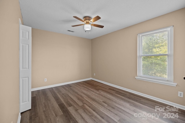 spare room with visible vents, ceiling fan, a textured ceiling, wood finished floors, and baseboards