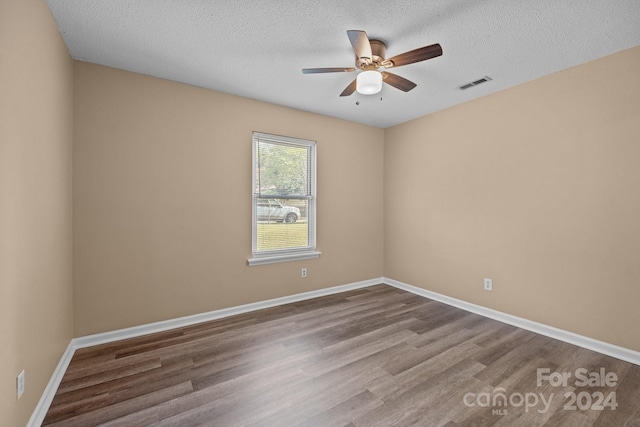 spare room with visible vents, a ceiling fan, a textured ceiling, wood finished floors, and baseboards