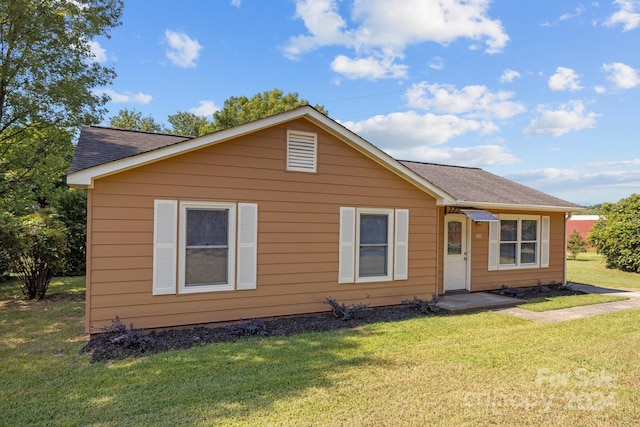 bungalow-style home with a front lawn and a shingled roof