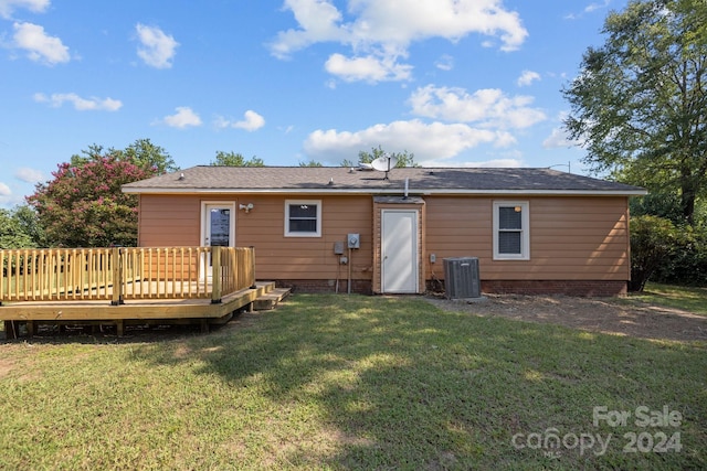 rear view of property with central air condition unit, a deck, and a lawn