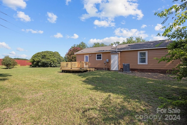 rear view of house with central AC unit, a lawn, and a wooden deck